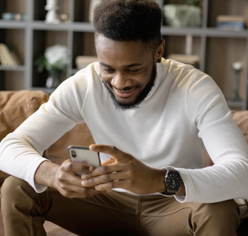 a young black man holding phone with both hands and looking into it 